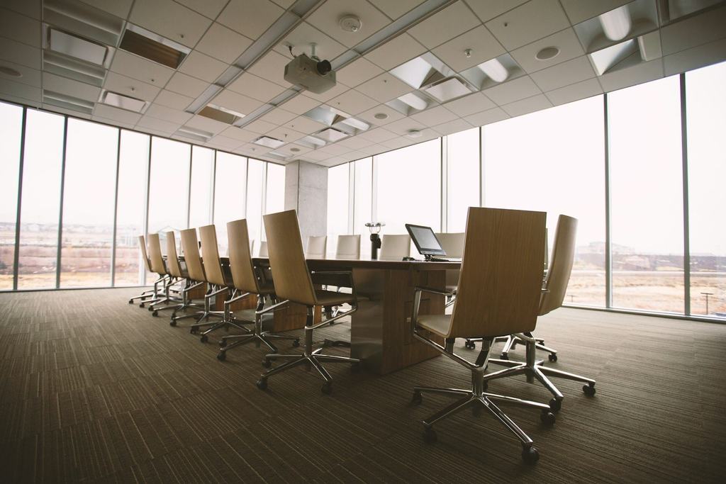 An empty conference room with a long table and tall windows looking out over the desert