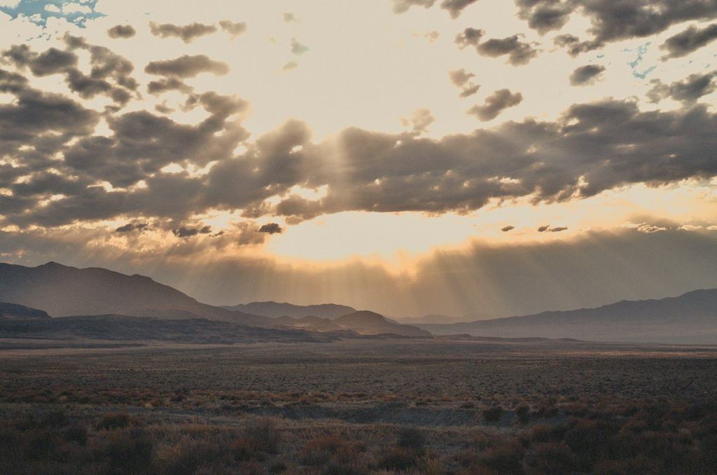 Sunlight breaking through clouds over a desert plain