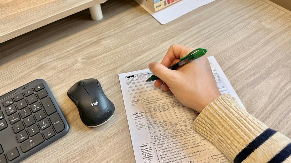 A hand writing on a paper form at a desk