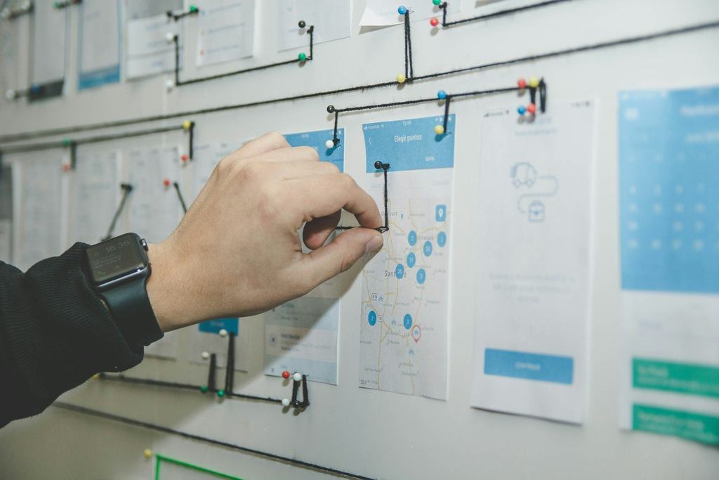 A hand pinning a card to a process-planning board