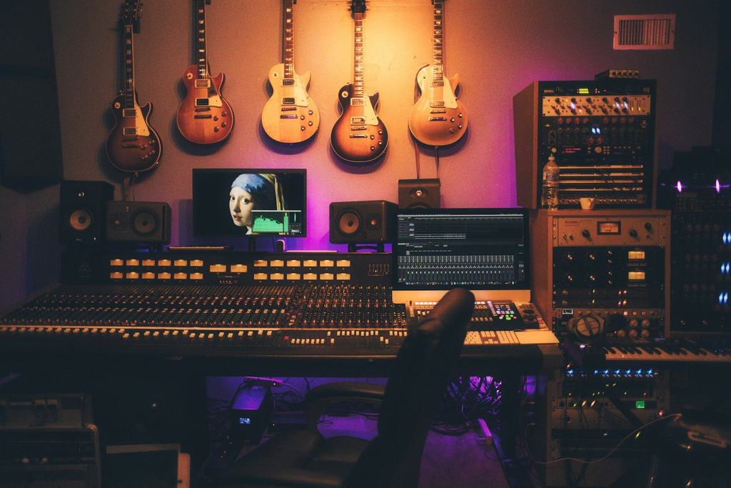A music studio with guitars on the wall and a large mixing console