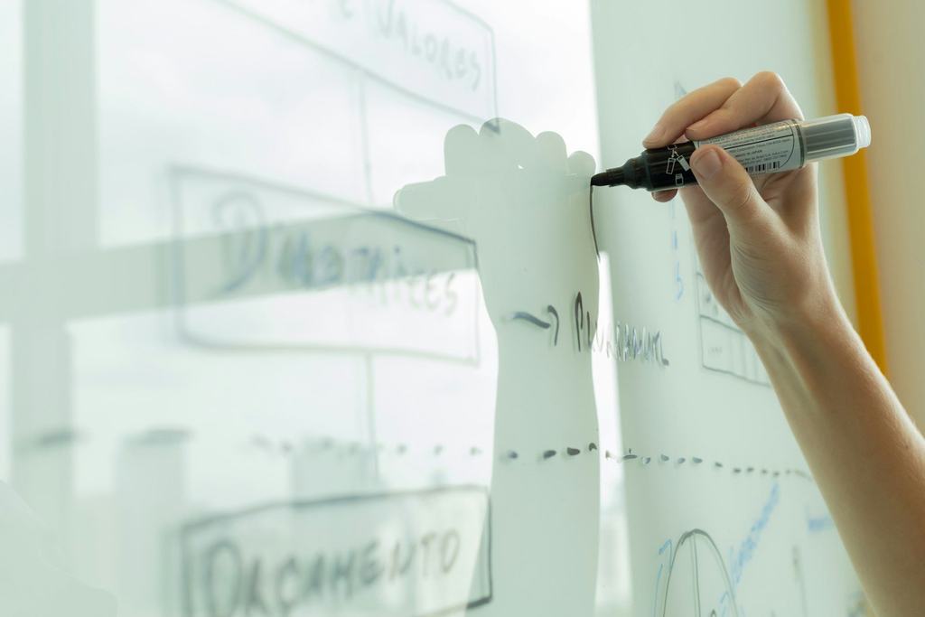 A hand drawing a diagram on a whiteboard